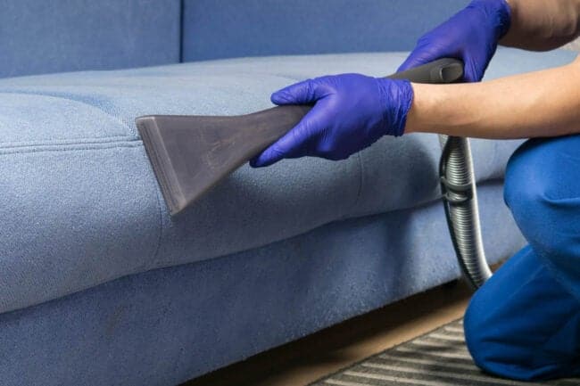 man professionally cleaning a couch with a hand held device