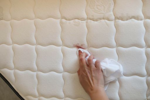Hand using tissue wiping mattress stain