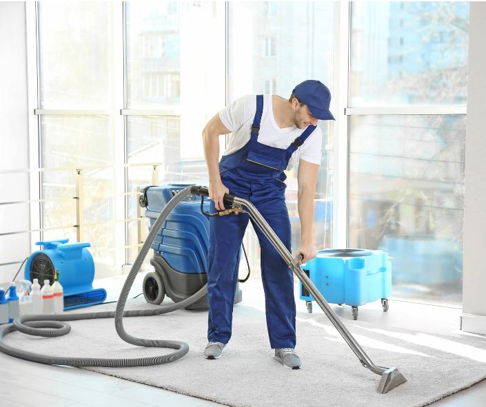 Man in uniform cleaning a carpet with a professional machine